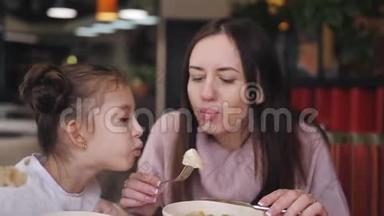 小女孩和妈妈在餐馆里吃热饺子。 妈妈把饺子吹<strong>凉了</strong>。